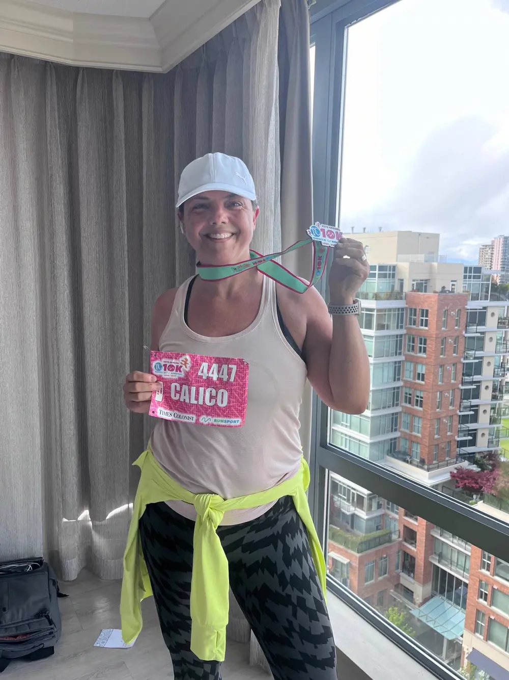 Woman holding up her race medal after finishing