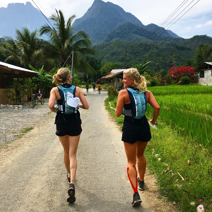Lizzie Wright trail running through a village with mountains behind