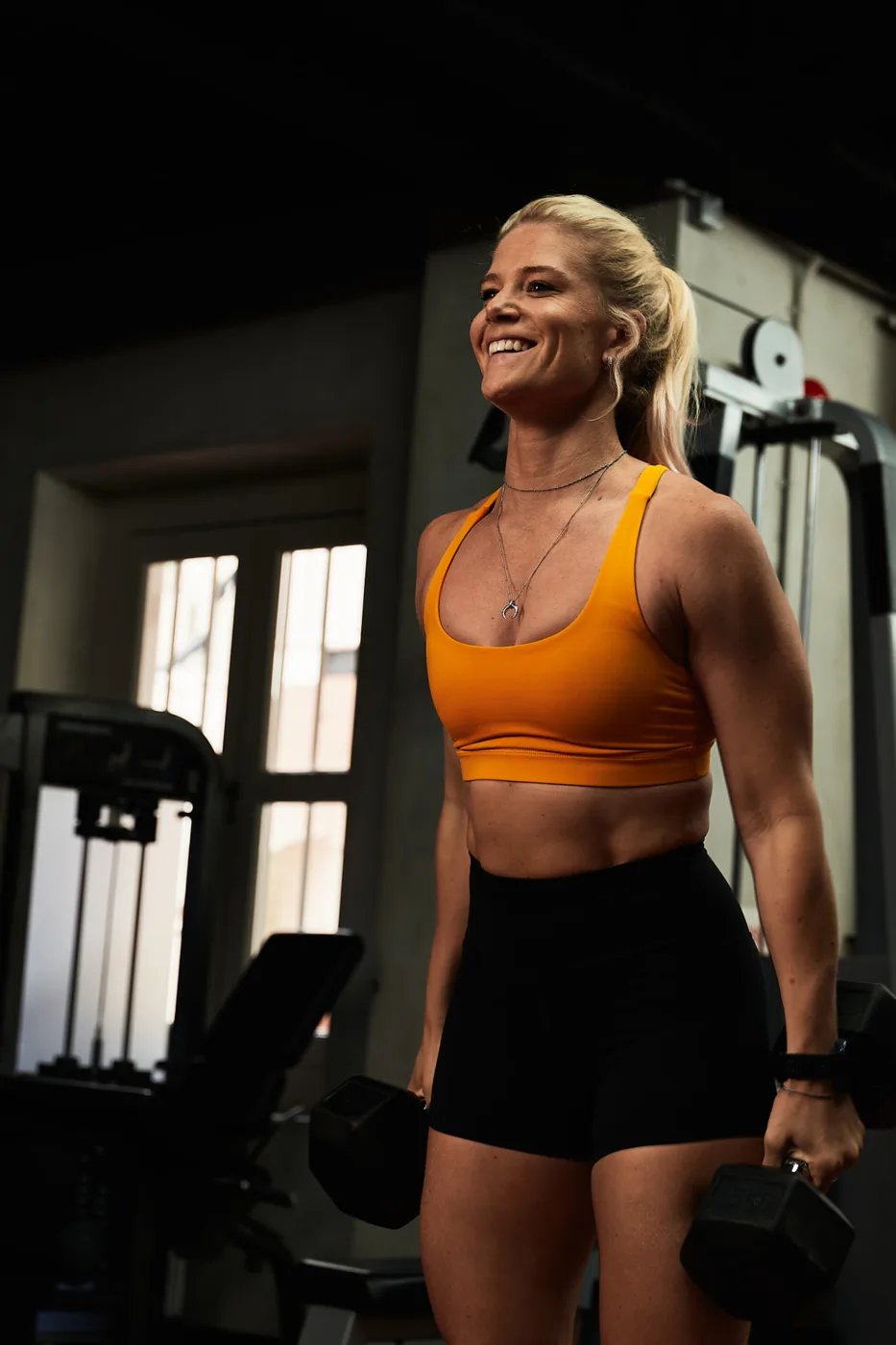 Lizzie smiling while holding dumbbells during a gym session