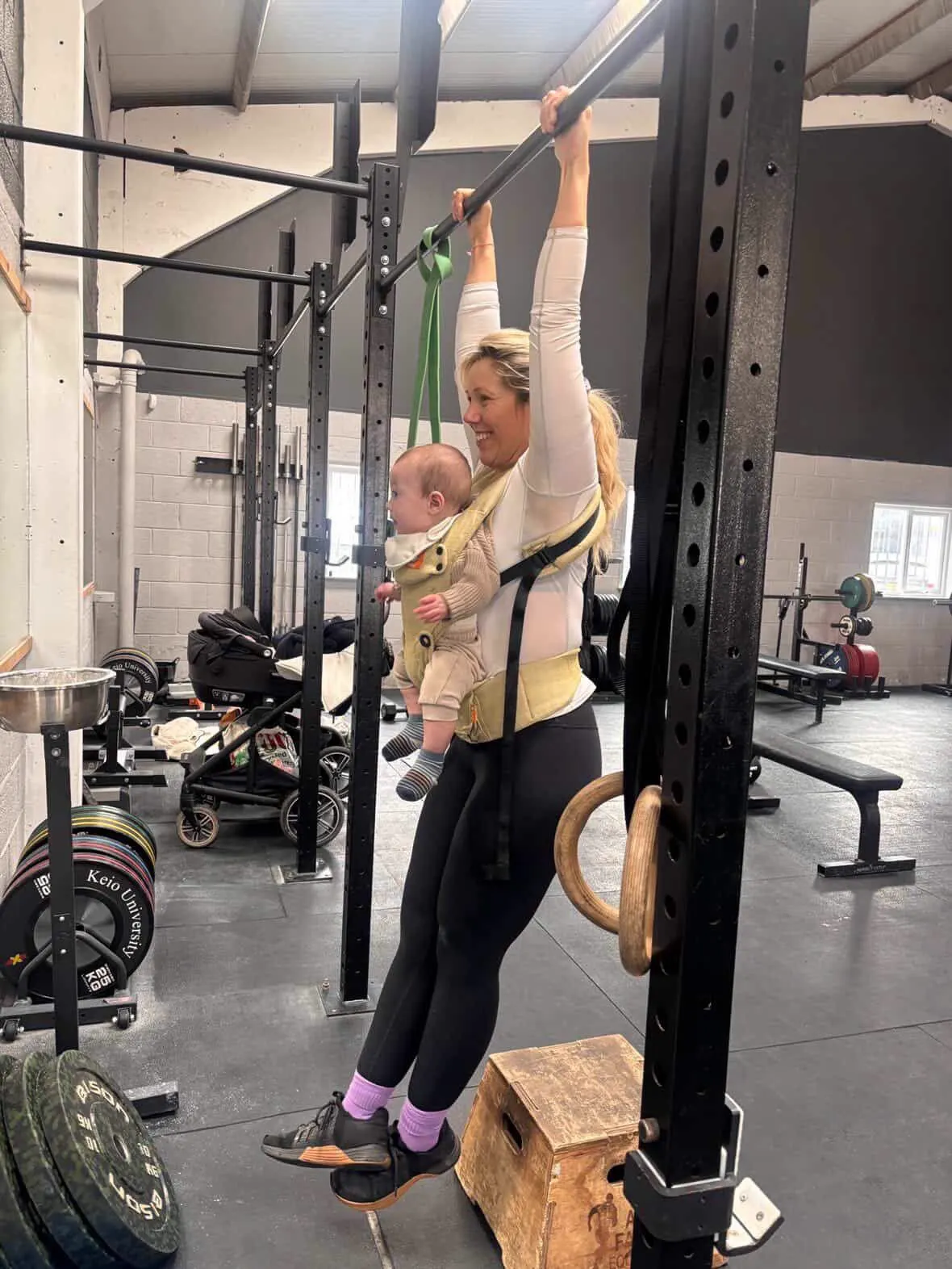 New mum doing pull ups with her baby in a carrier