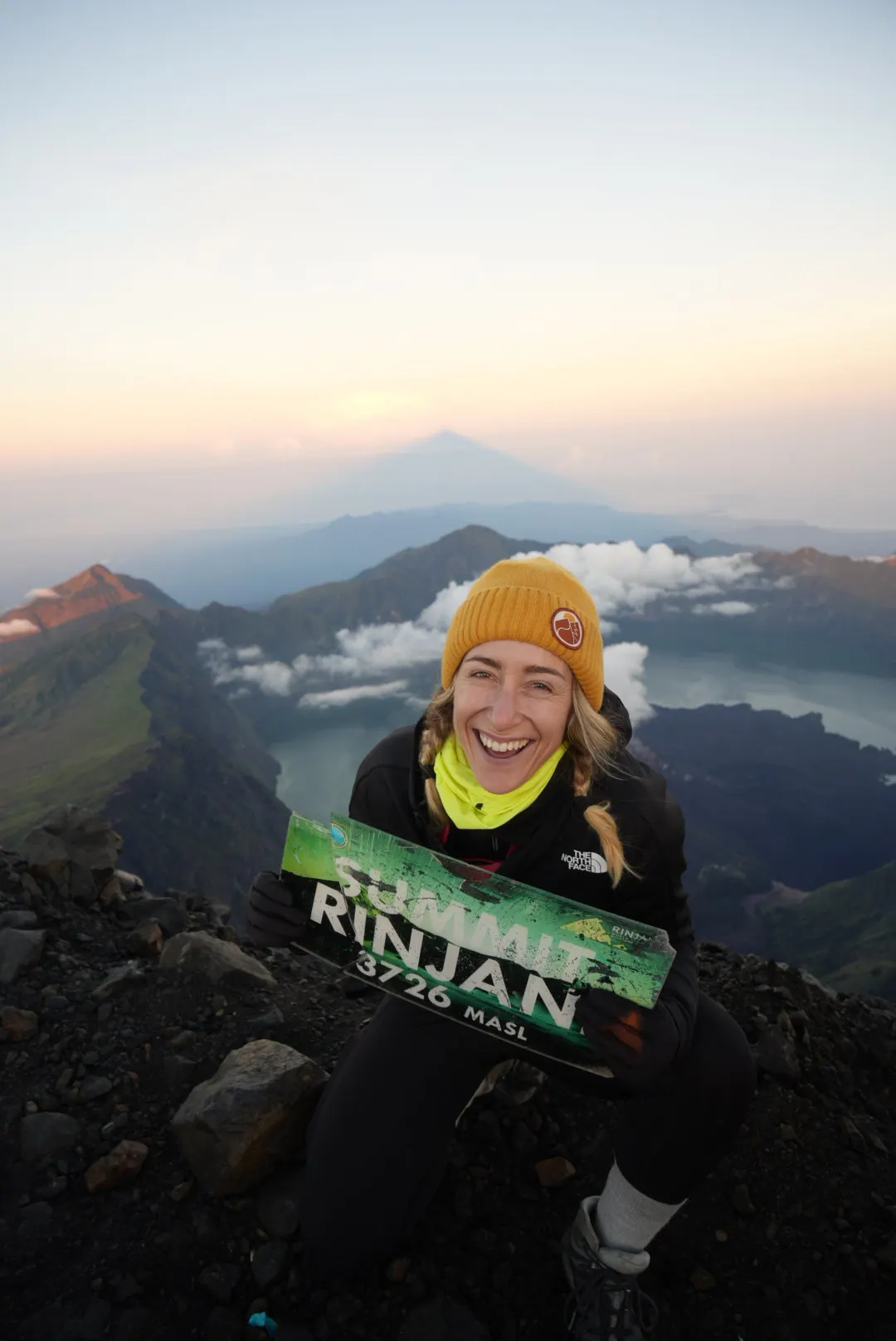 Woman celebrating at the summit of Mount Rinjani at sunrise