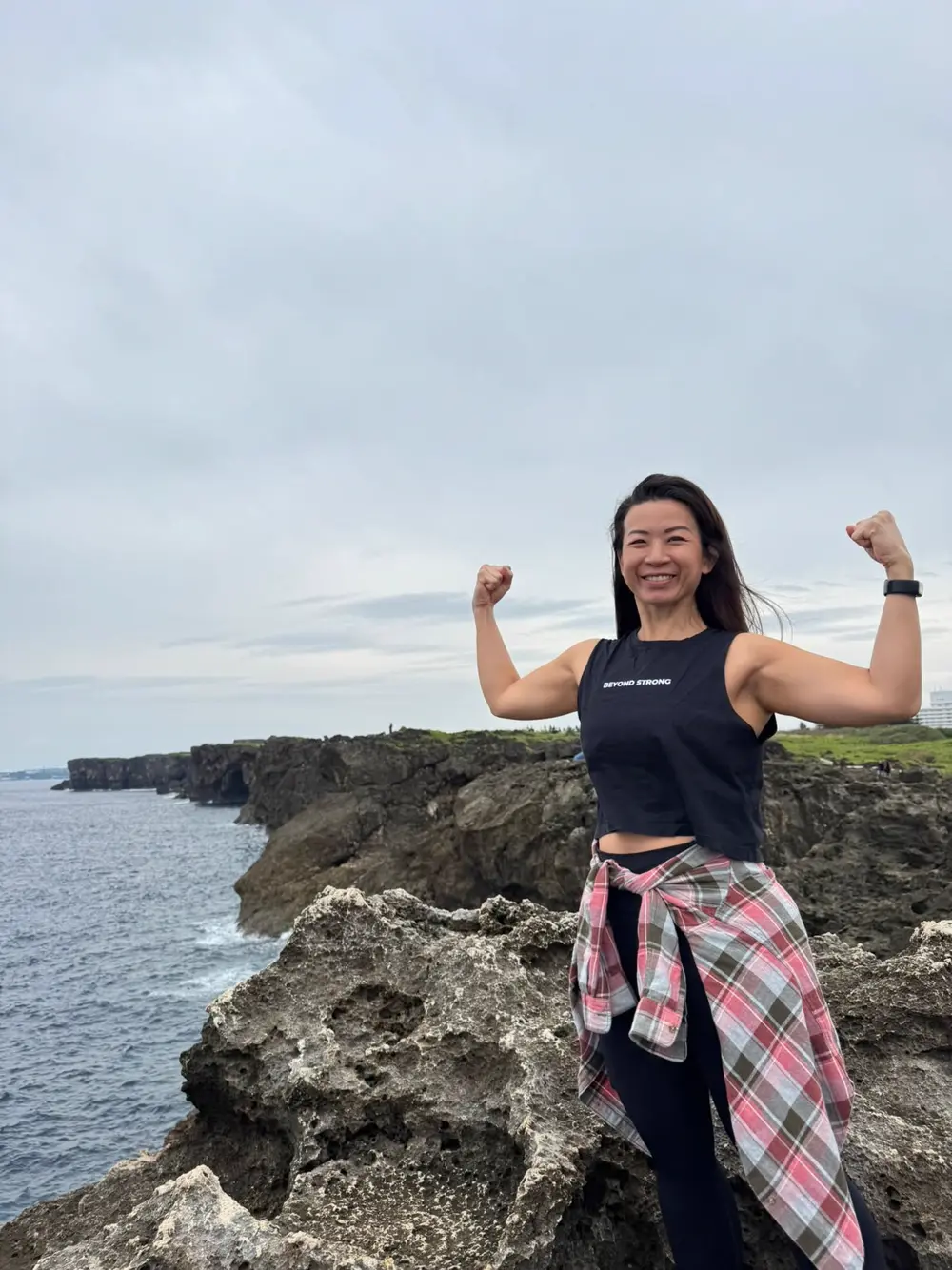 Client flexing on a clifftop by the ocean